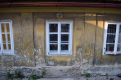 Pohled na jižní fasádu domu a zdánlivě staré okno. Okno pochází z 60. let 20. století a původně se zde nacházely dřevěné dvoukřídlé vstupní dveře (viz cihelné zdivo objevující se pod opadanou omítkou). Foto: Jiří Chmelenský.